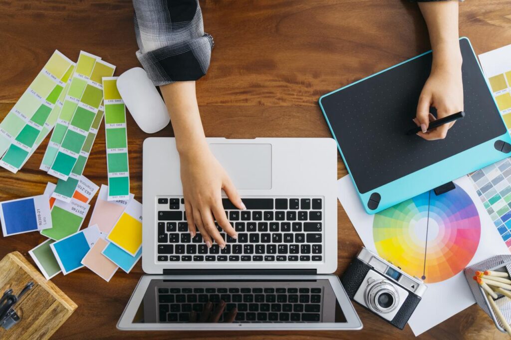 A graphic designer compares colour shades while drawing on a tablet and using a laptop