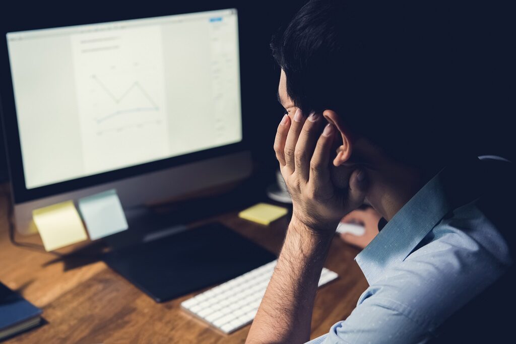 A stressed employee stares at his monitor, unable to work effectively.