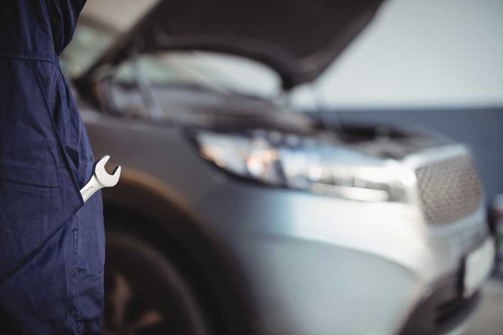 Mid-section of mechanic with a wrench tool in pocket at garage